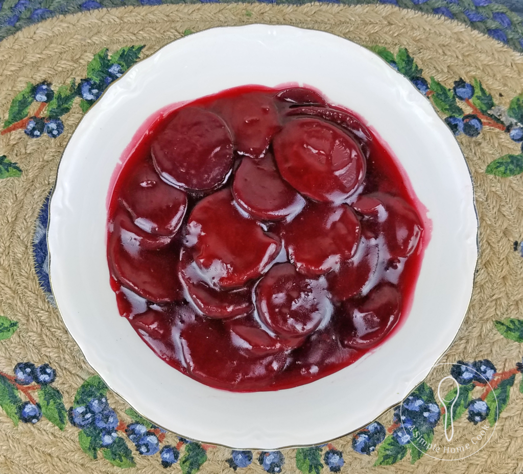 Bowl of sliced beets in sauce on a mat